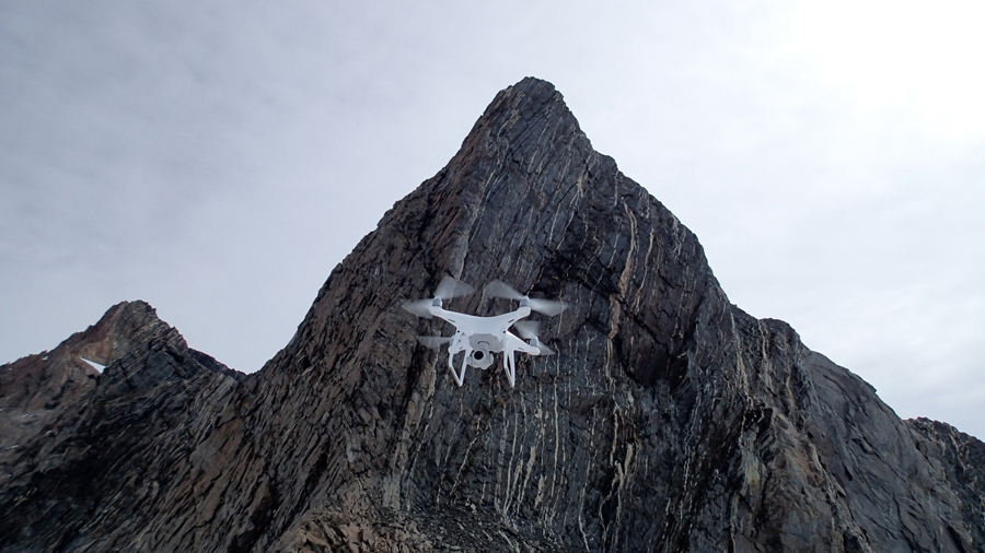 A drone flying in front of a rock face