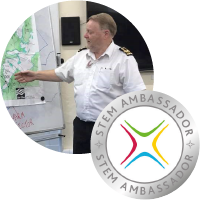 A photo of Peter Greenhalgh standing in front of a whiteboard. The STEM Ambassador logo.